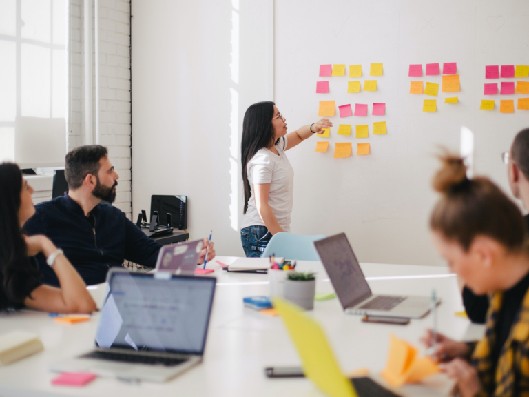 A workshop room with one participant at a wall of post it notes