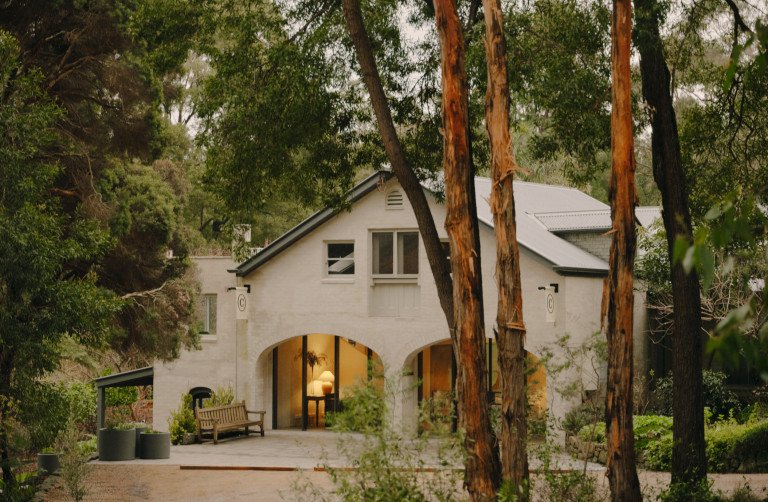 two story building in a bush setting. the front room is lit up