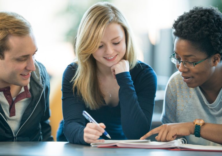3 people looking at notes in a notebook