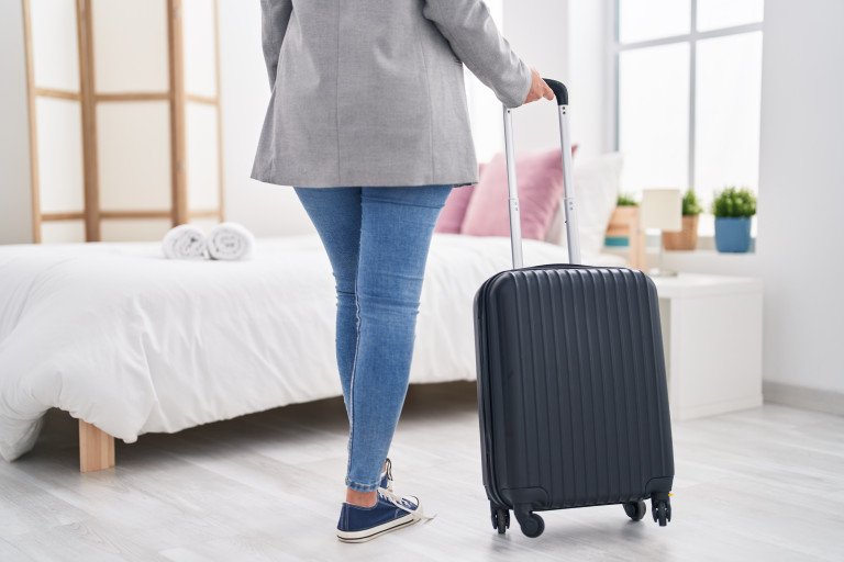 Young woman business worker holding suitcase walking at hotel room