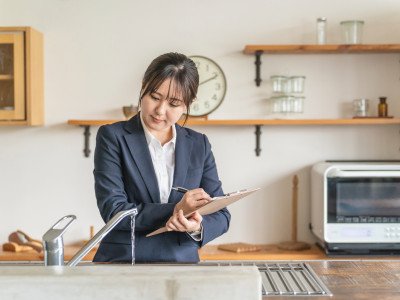 woman with clipboard checking water from a tap in kitcehn