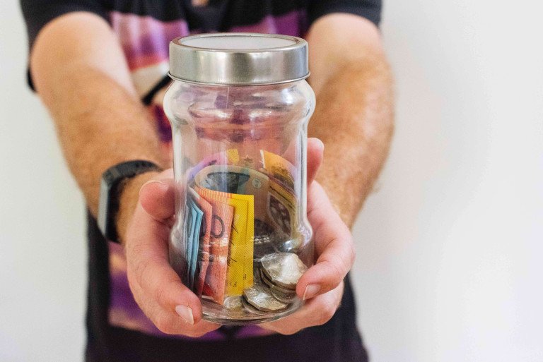 a jar of australian money with both coins and notes
