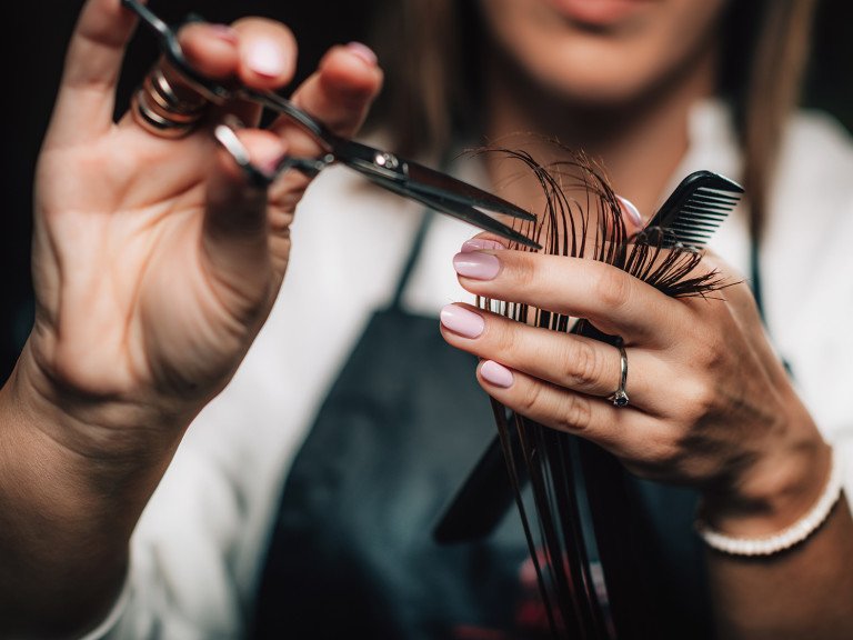 Close-up of a hairdresser cutting woman’s hair.
