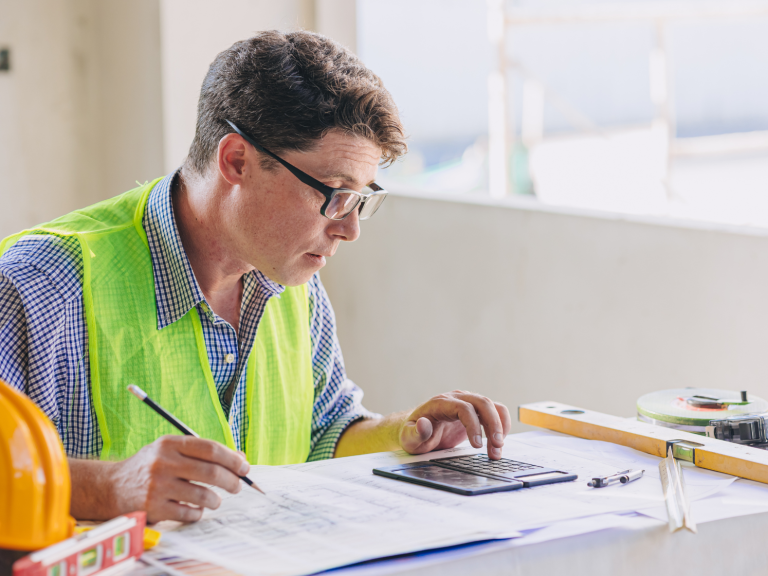 Builder sitting at a table doing his finances with a calculator