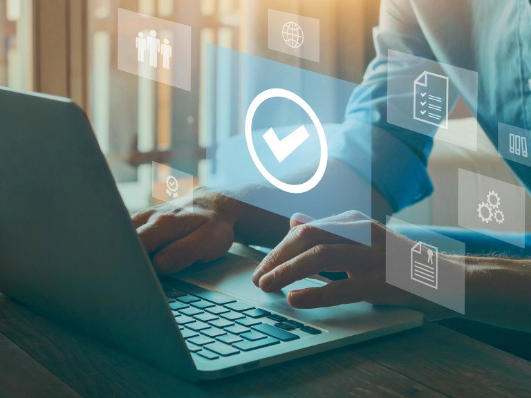 Person typing at computer with graphic elements showing people, awards, checklist, internet