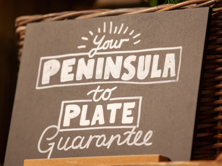 The words 'Your Peninsula to plate guarantee,' written on a chalkboard sign